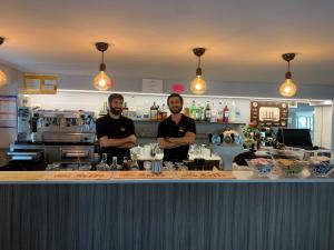 two men standing behind a bar in a kitchen at Hotel Capri in San Benedetto del Tronto