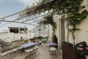 un patio al aire libre con mesas, sillas y plantas en L'Arturo B&B, en Matera