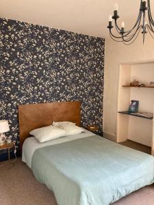 een slaapkamer met een bed met een bloemaccentmuur bij Casa Bella in Charroux-dʼAllier