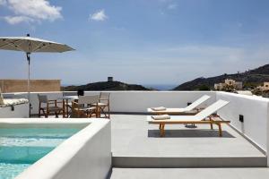 um pátio com uma piscina, cadeiras e um guarda-sol em Lerion Luxury Villas em Akrotírion