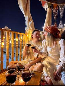 a man and woman sitting on a deck drinking wine at NAZIRA Boutique Hotel in Khiva