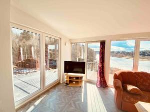 sala de estar con TV y ventanas grandes en Bjurviks Villa - Flat 3 en Flen