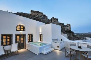 a white house with a swimming pool and a table at Lerion Luxury Villas in Akrotiri