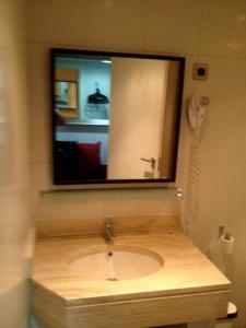 un bagno con lavandino e specchio di PUERTA DEL SOL Carretas APARTAMENTS & Rooms a Madrid Altre 22 foto