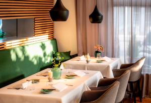 zwei Tische in einem Restaurant mit weißen Tischdecken in der Unterkunft Das Eckert - Lifestyle Design Hotel & Fine Dining bei Basel (Grenzach) in Grenzach-Wyhlen