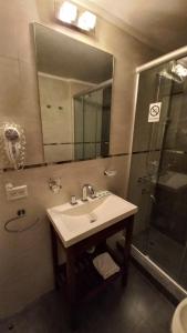 een badkamer met een wastafel en een douche met een spiegel bij Costanera Hotel in Puerto Madryn