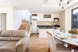 ein Wohnzimmer und eine Küche mit einem Tisch und einer Couch in der Unterkunft Casa Neves em Bombas in Bombinhas