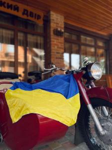 un motocycle portant un drapeau sur son côté; dans l'établissement Батярський Двір, à Pasiky-Zubryts'ki