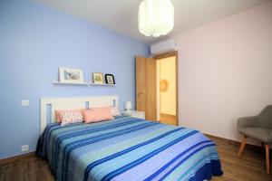 um quarto azul com uma cama e uma cadeira em Mimosa House Cabanas em Cabanas de Tavira