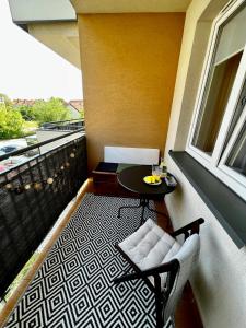 einen Balkon mit einem Tisch, einem Stuhl und einem Fenster in der Unterkunft Klimatyczne mieszkanie w centrum Giżycka in Giżycko