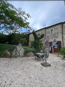 um guarda-chuva e um banco em frente a um edifício em Agriturismo San Pietro em Castiglione dʼOrcia