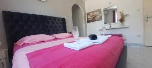een roze bed met twee handdoeken en twee glazen erop bij Studio Apartments Jupo in Ulcinj