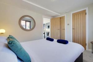 een slaapkamer met een groot wit bed met blauwe kussens bij Windham Mews - Stunning Flat in Seaside Town in Bournemouth