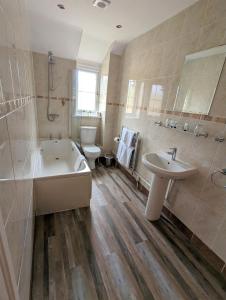 a bathroom with a tub and a sink and a toilet at The Lodge by Cefn Tilla in Usk