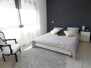 ein Schlafzimmer mit einem Bett, einem Stuhl und einem Fenster in der Unterkunft Villa proche de Montpellier et des plages in Castelnau-le-Lez