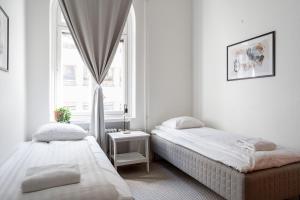 two beds in a white room with a window at 2ndhomes Tampere "Ruuskanen" Apartment - 3 Bedrooms, Best Location & Sauna in Tampere