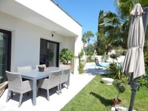 eine Terrasse mit einem weißen Tisch, Stühlen und einem Sonnenschirm in der Unterkunft Villa proche de Montpellier et des plages in Castelnau-le-Lez