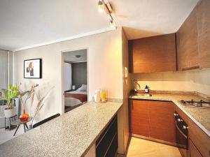 a kitchen with a sink and a room with a bed at Depto CostaneraCenter in Santiago