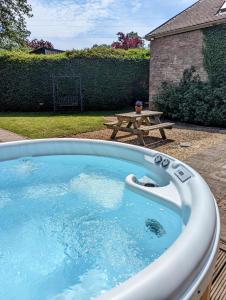 a hot tub in a backyard with a picnic table at Cecile's Cottage at Cefn Tilla Court, Usk in Usk