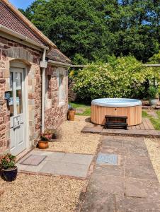 a patio with a large tub in a yard at Cecile's Cottage at Cefn Tilla Court, Usk in Usk