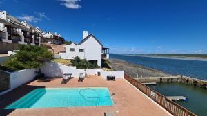 a swimming pool on top of a building next to the water at River View Cottage - at the Breede in Witsand