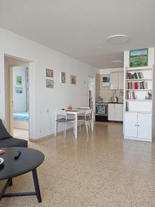 a living room with a table and a kitchen at Cozy apartment with good vibe in Ashdod