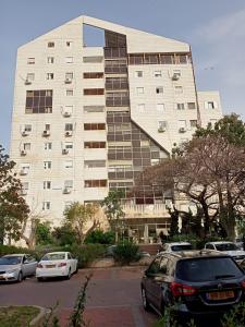 un gran edificio con coches estacionados frente a él en Cozy apartment with good vibe en Ashdod