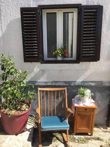 einen Holzstuhl und einen Tisch mit einem Fenster in der Unterkunft Apartment 'Dan' in Zlarin