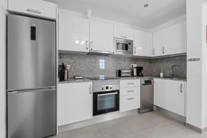 a kitchen with white cabinets and stainless steel appliances at Home2Book Charming Private Pool Puerto del Carmen in Tías