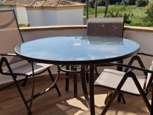 un tavolo in vetro e 2 sedie sul balcone di En Denia, urbanización el palmar con piscina, toboganes y chiringuito a Denia