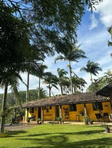 a yellow house with palm trees in front of it at Pousada Recanto dos Pássaros in Lindóia