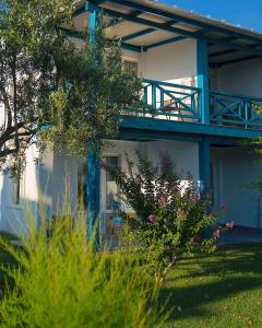 a white house with a blue balcony and some plants at Club Afrodit Tatil Köyü in Altınoluk
