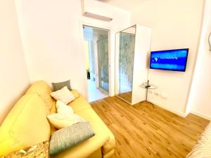 a living room with a yellow couch and a tv at Appartamento Alice Smart in Bardolino