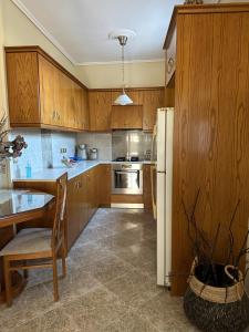 een keuken met houten kasten, een tafel en een koelkast bij Gavrilis Apartments in Nénita