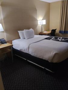 a hotel room with a large bed with white sheets at La Quinta by Wyndham West Palm Beach Airport in West Palm Beach