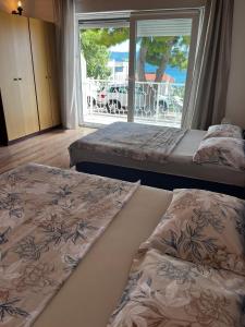 two beds in a room with a large window at Apartmani Branko Vojnovic in Omiš