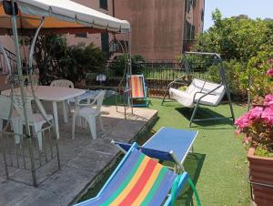 un patio con sillas, mesa y columpios en Noemi Apartment 5 Lands Paradise en Levanto