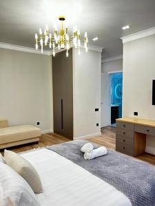 sypialnia z dużym białym łóżkiem i żyrandolem w obiekcie Talan life aparts w mieście Atyrau