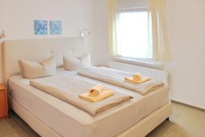 a white bedroom with two towels on a bed at Pension An der Kamske, DZ 4 in Lübbenau