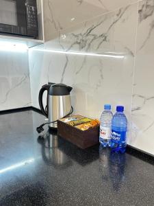 a counter with two bottles of water and a coffee pot and a box of food at Talan life aparts in Atyraū