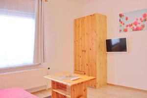 Habitación con mesa y TV en la pared. en Pension An der Kamske, FZ 5 Familien, en Lübbenau