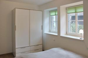 a bedroom with a white cabinet and two windows at Hopkas Remise in Lehde