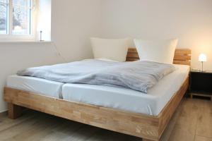 1 cama con sábanas blancas y marco de madera en Hopkas Remise, en Lehde