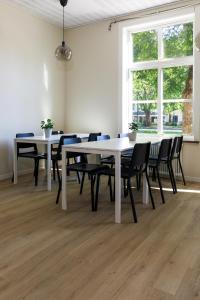 un comedor con mesas blancas y sillas negras en Nicolai B&B, en Lidköping