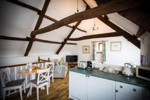 a kitchen with white cabinets and a table in a room at The Den at Country Ways in Atherington