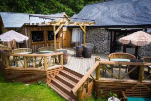 a wooden deck with chairs and tables and a building at The Den at Country Ways in Atherington