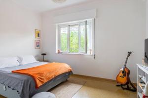 - une chambre avec un lit doté d'une couverture orange et d'une guitare dans l'établissement Luce's Home, à Palerme