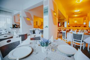 Hotel Tusnad في بايلي توشناد: غرفة طعام مع طاولات بيضاء وكراسي بيضاء