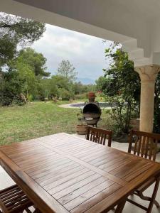 Villa avec piscine privée في طبرقة: طاولة وكراسي خشبية على شرفة مع شواية