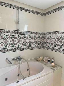 a bath tub in a bathroom with a tile wall at Villa avec piscine privée in Tabarka